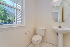 Stylish light fixture, pedestal sink and ceramic tile floor .