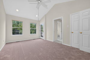 The primary bedroom features a cathedral ceiling, recessed lighting, ceiling fan, walk-in closet, and NEW CARPETING, with direct access to a private deck.