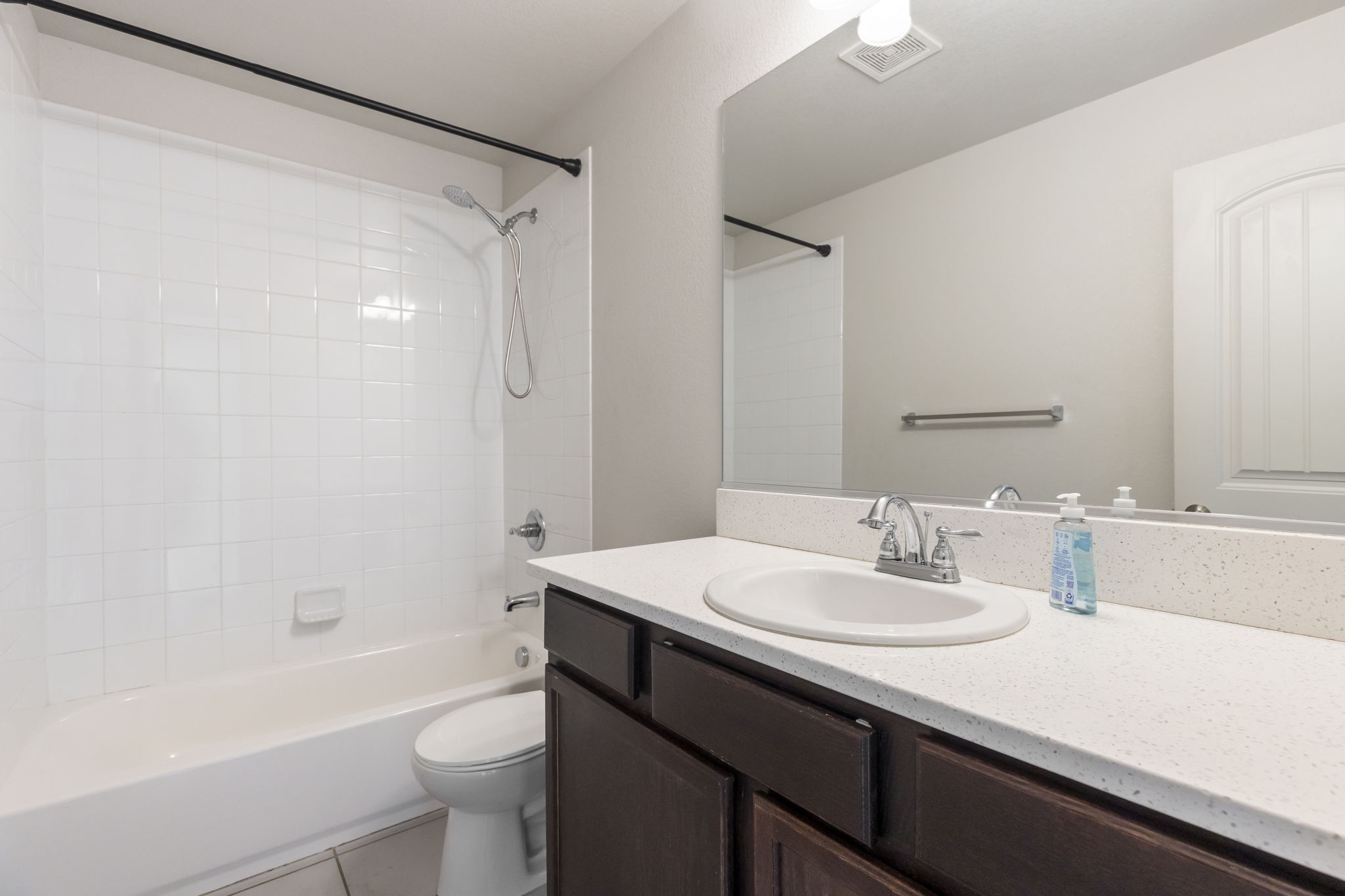 Main floor full bathroom adjacent to bedroom  with tub/shower combination, vanity, and tile flooring