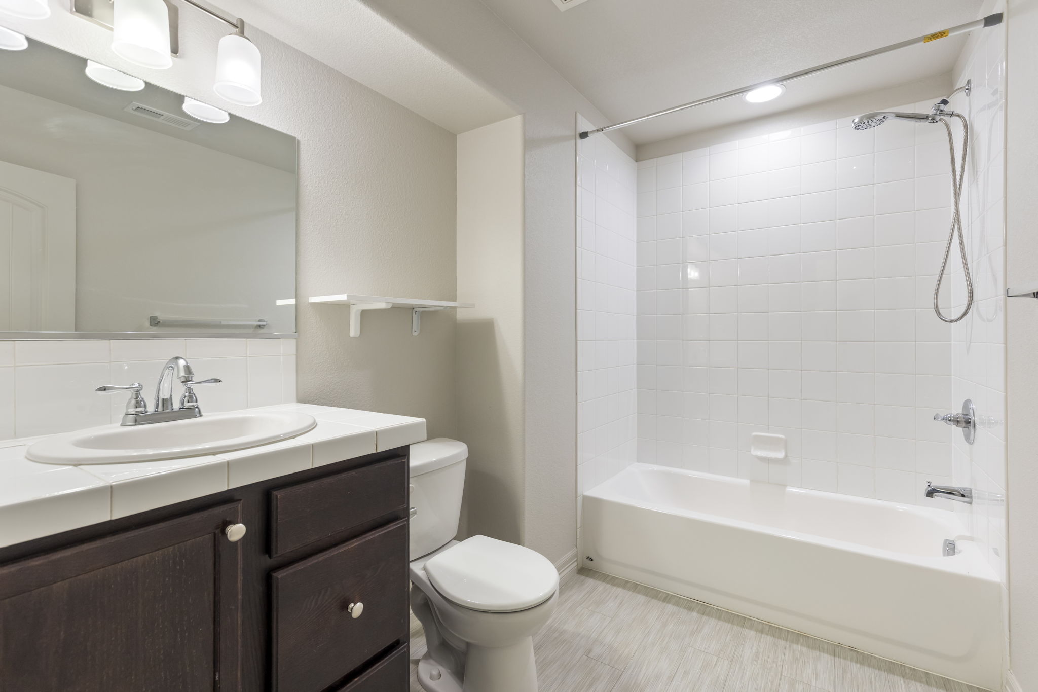 Basement full bathroom with tub/shower combination, vanity, and tile flooring.