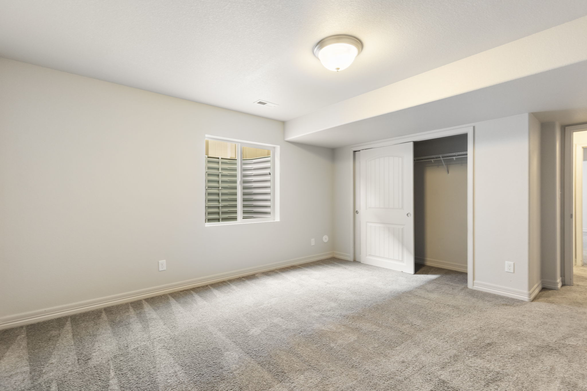 Alternate view of basement bedroom showing flexible layout and closet access.