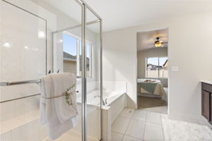 Primary bathroom featuring a soaking tub, walk-in shower with glass enclosure, and tile flooring.