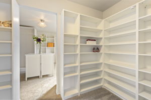 Custom double walk-in closet featuring built-in drawers, shelving, and hanging space.