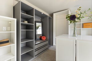 Custom double walk-in closet featuring built-in drawers, shelving, and hanging space.