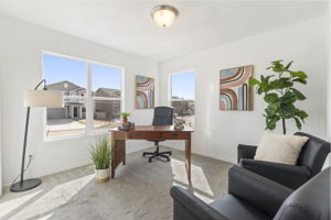Main-level bedroom or flex room with natural light, and carpeted flooring.