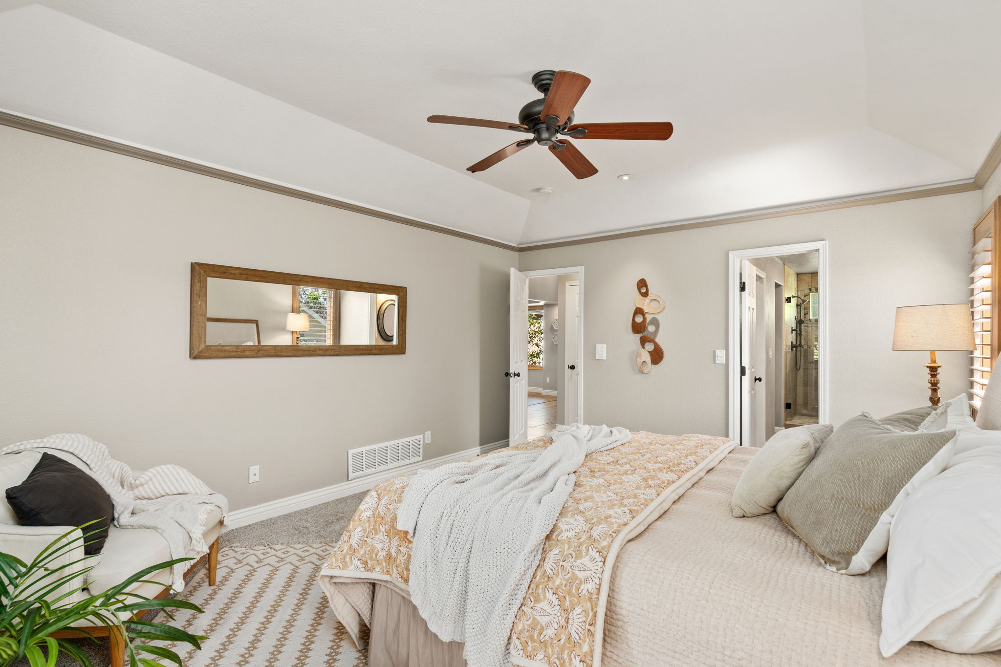 Main floor primary bedroom with tray ceiling, custom wood shutters, ensuite bathroom and walk-in closet.