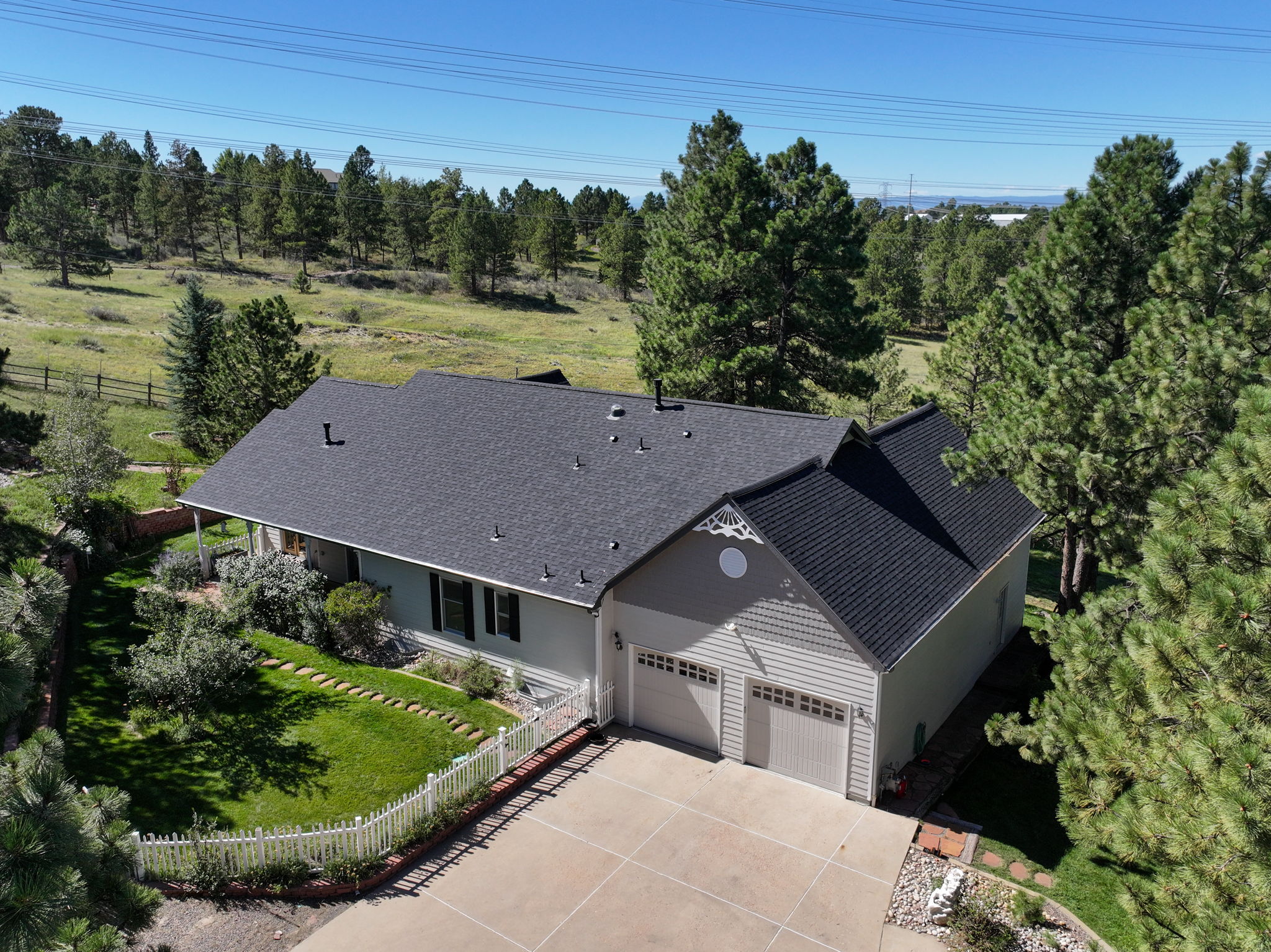 Great view of the back of the home, complete with a 4 car tandem garage and a white picket fenced backyard.