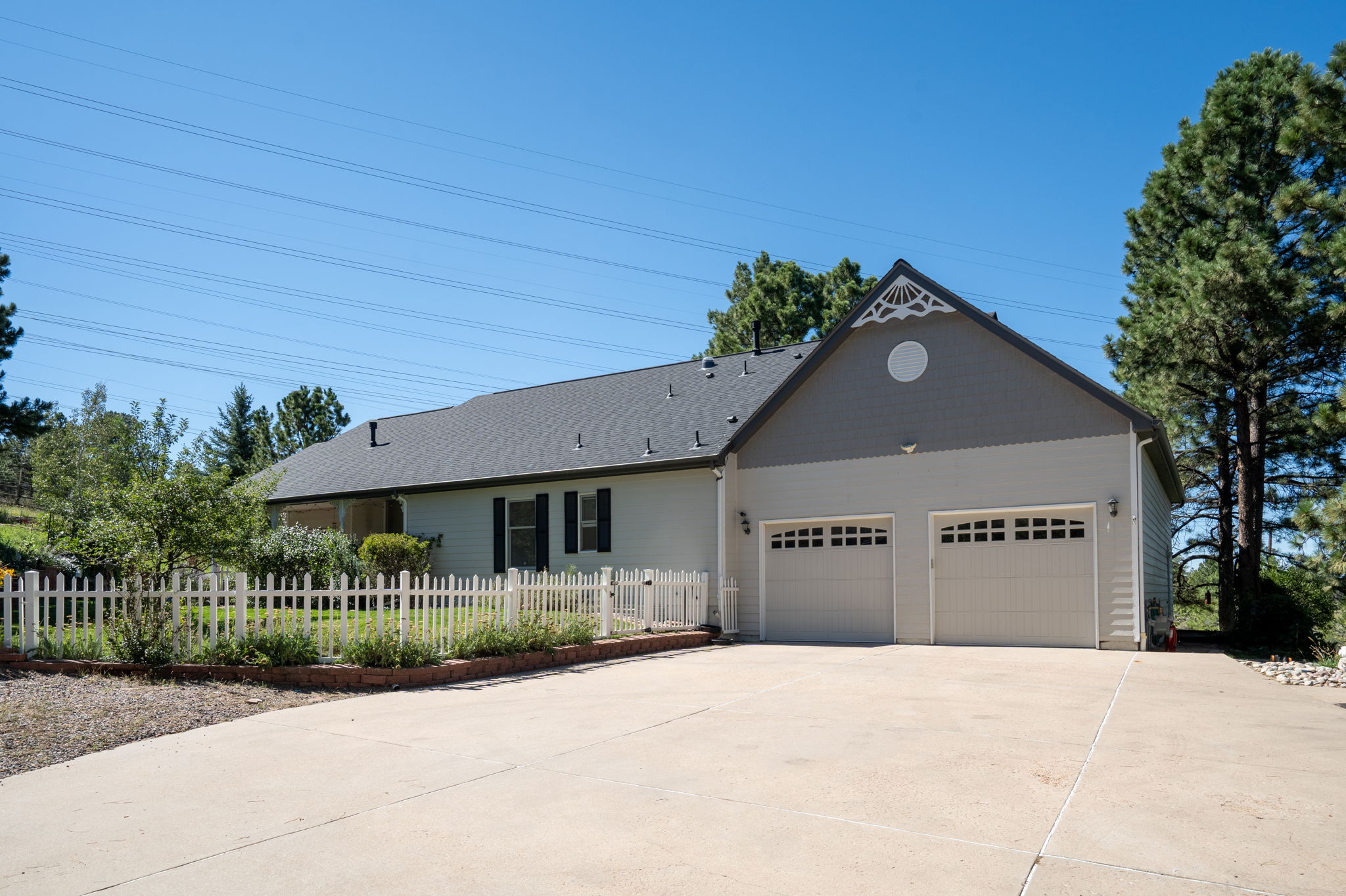Great view of the back of the home, complete with a 4 car tandem garage and a white picket fenced backyard.