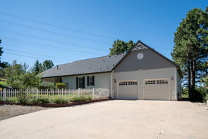 Great view of the back of the home, complete with a 4 car tandem garage and a white picket fenced backyard.