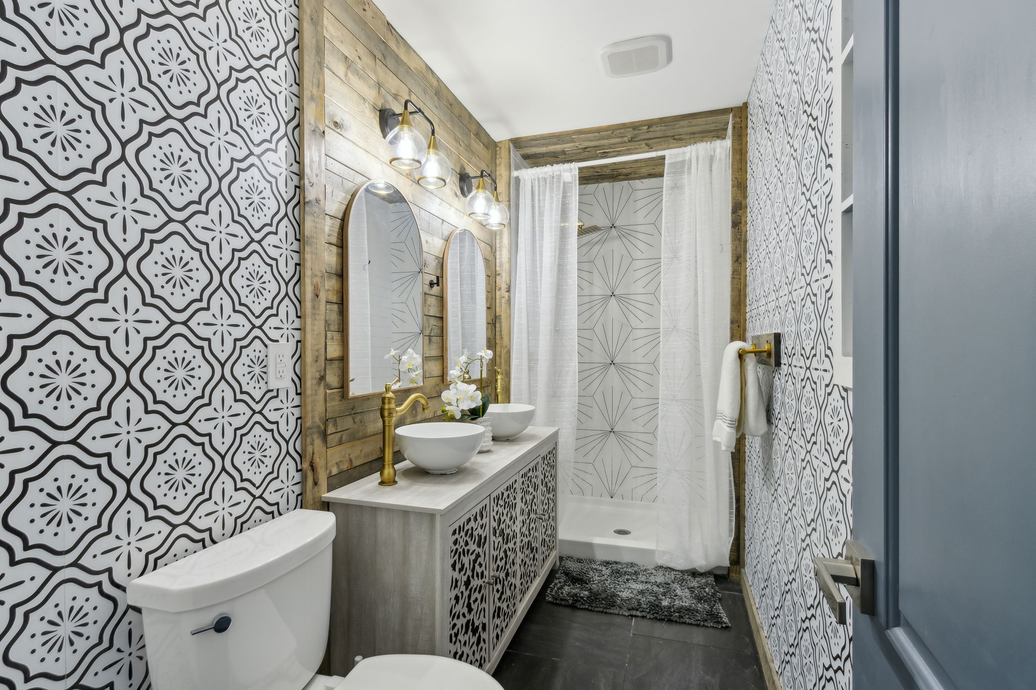 In the master bath, a statement vanity pairs effortlessly with rustic accents, stylish wallpaper ...