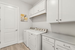 Separate laundry room featuring a storage closet and cabinets for maximum organization.