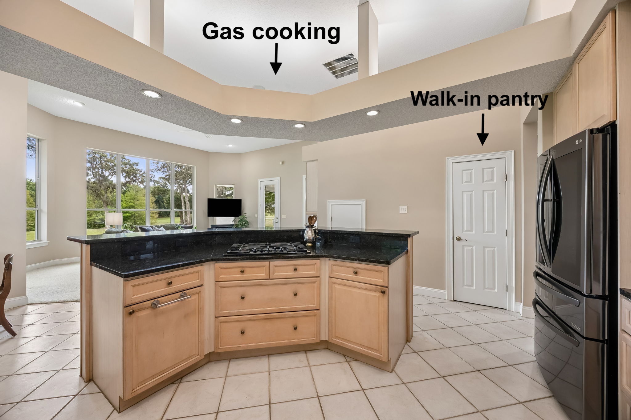 The gas cooktop is positioned so the chef can face the room — and the fairway views beyond.