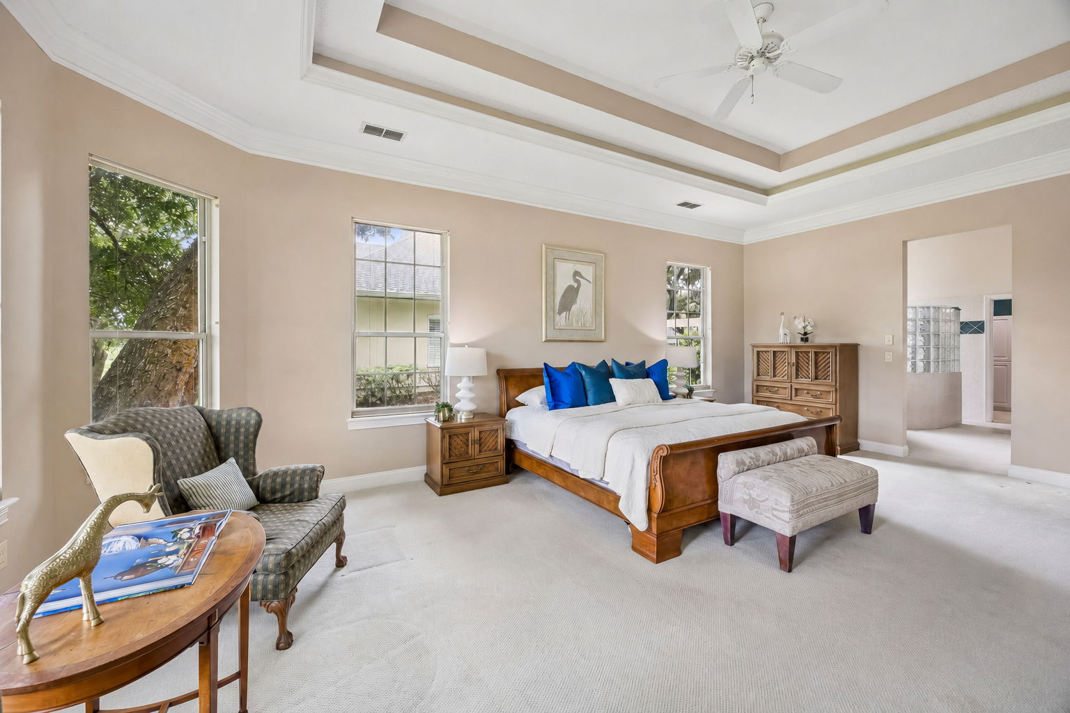Soft natural light, tray ceilings, and room to unwind give the bedroom a calm retreat-like feel.