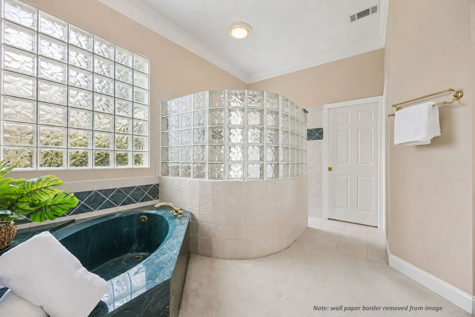 The bath offers a soaking tub, glass-block privacy, and a generous walk-in shower area.