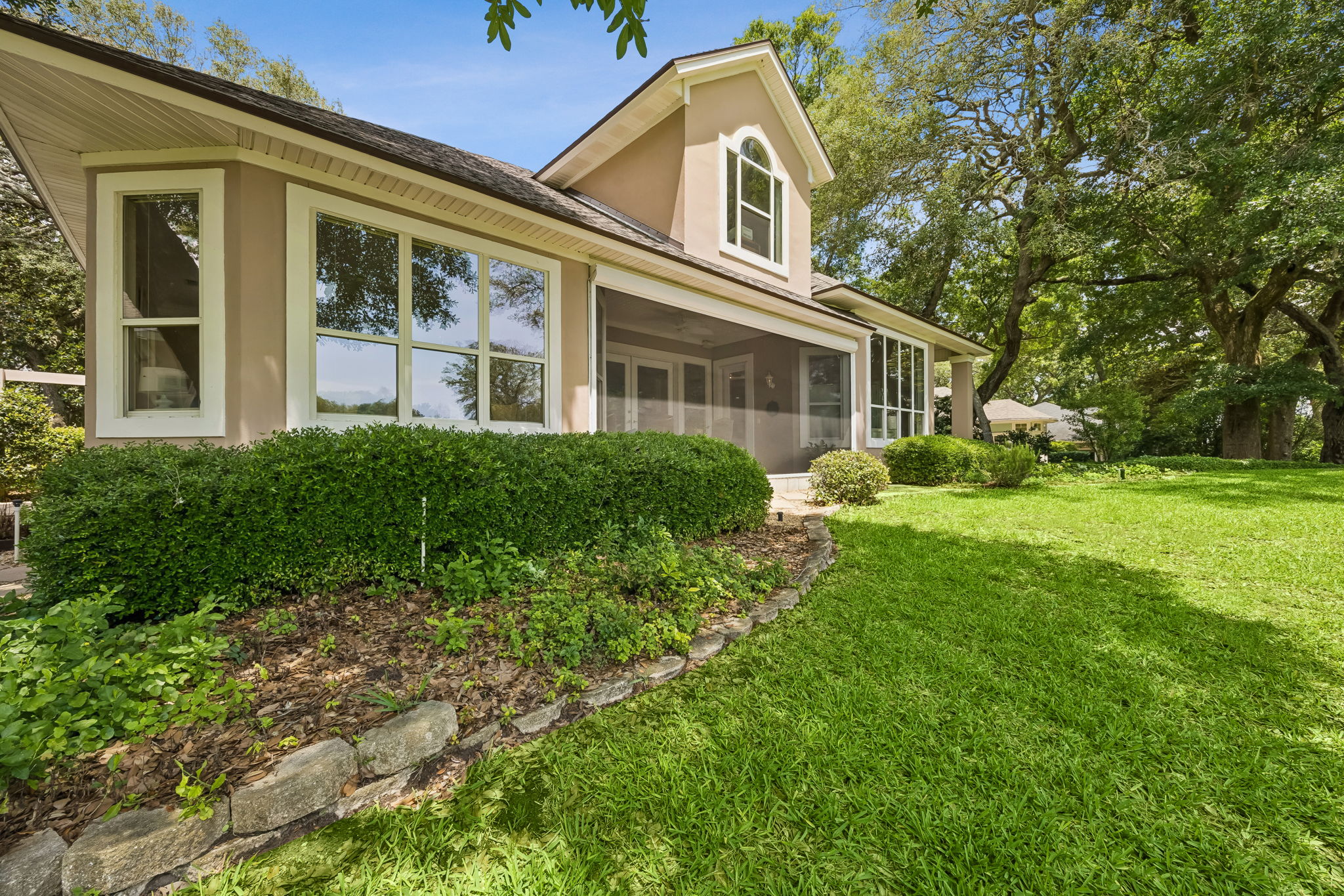 The rear elevation opens beautifully to the lawn, trees, and screened golf-front living area.