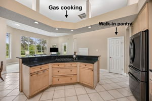 The gas cooktop is positioned so the chef can face the room — and the fairway views beyond.