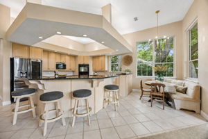 The kitchen opens naturally to a sunny breakfast nook, where windows frame the trees and golf course outside...