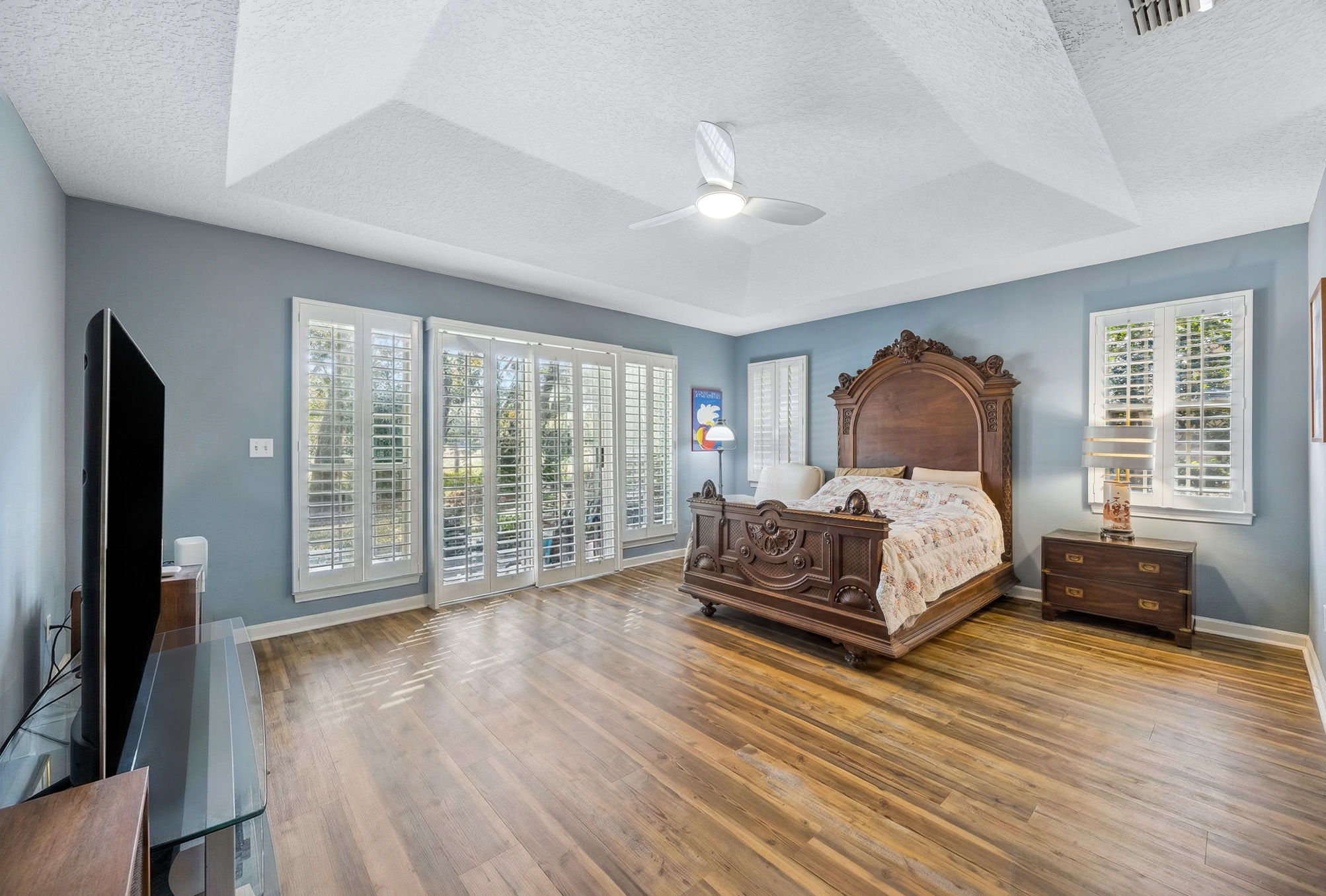 The primary suite is generously scaled, with a tray ceiling, plantation shutters, and a calm, tucked-away feel.