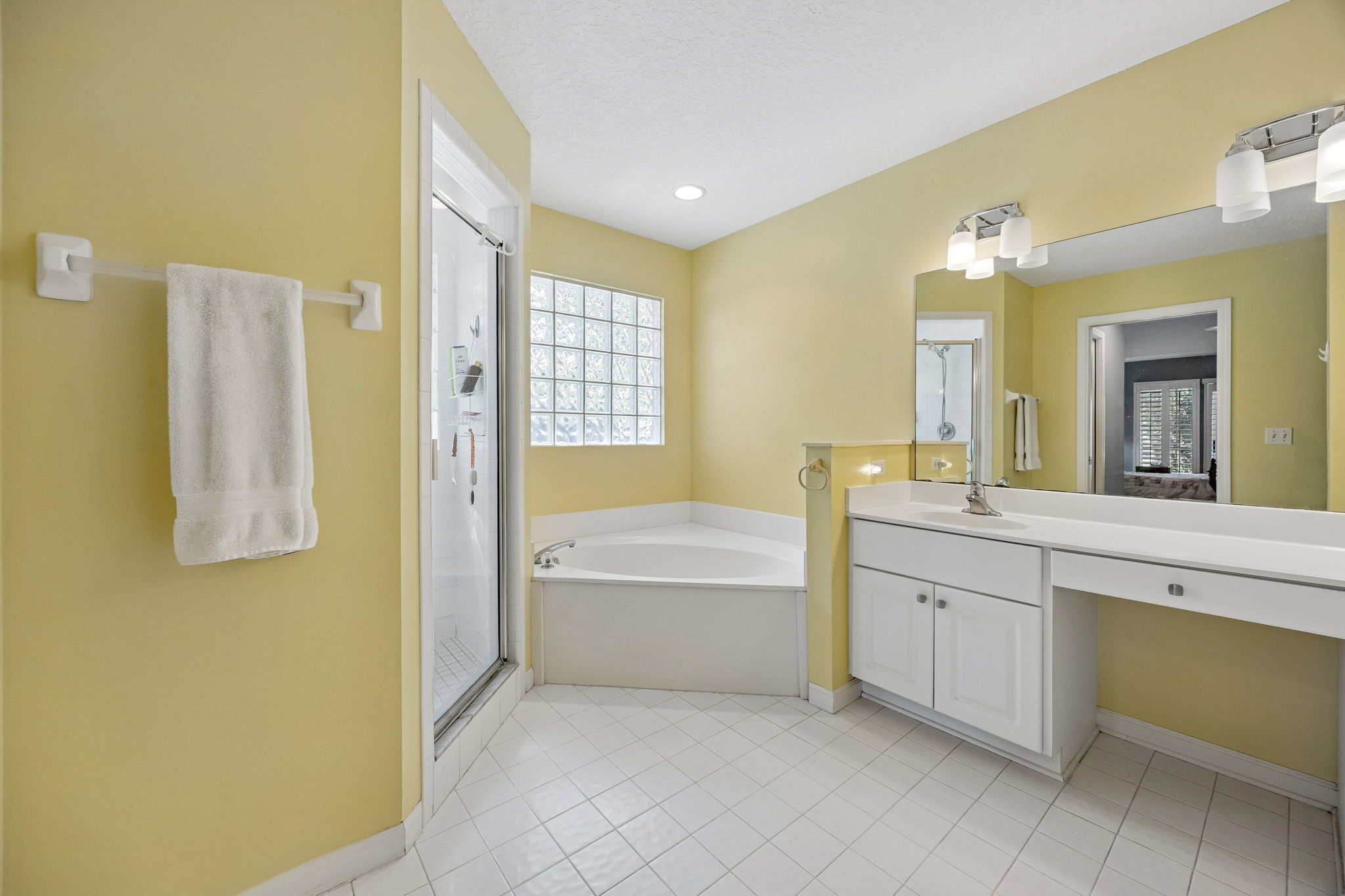 The ensuite bath is spacious in scale, with large vanity ...