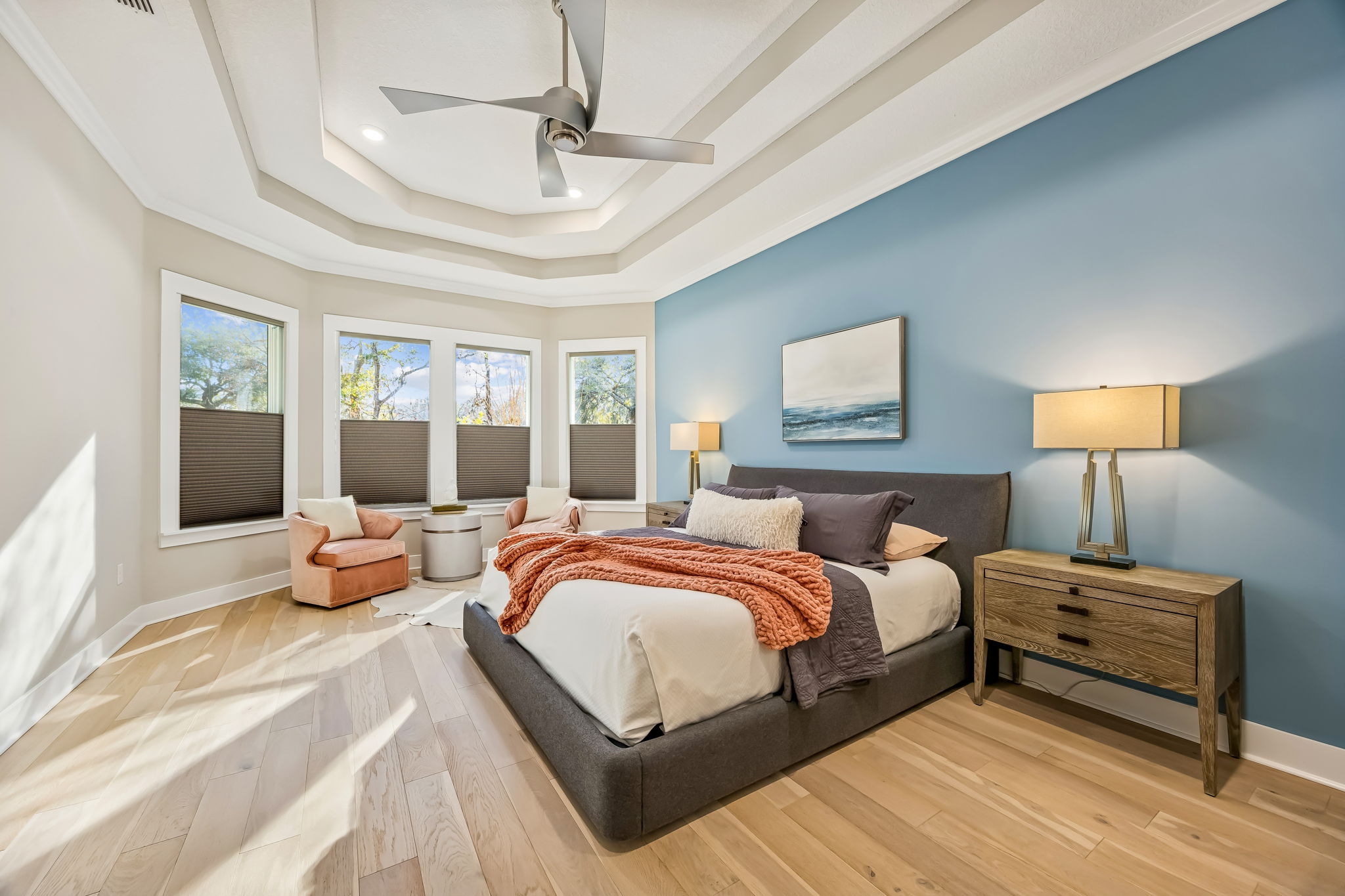 The oversized primary suite features a wall of windows overlooking the backyard ...