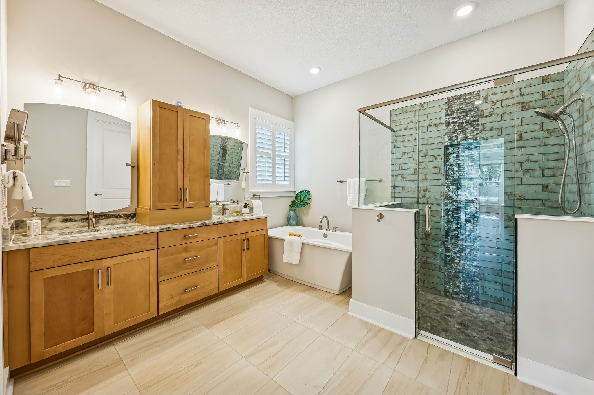 The beautifully appointed primary bath features warm maple-toned cabinetry ...