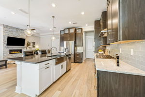 The kitchen balances warmth and contrast with a deep mocha quartz island ...