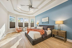 The oversized primary suite features a wall of windows overlooking the backyard ...