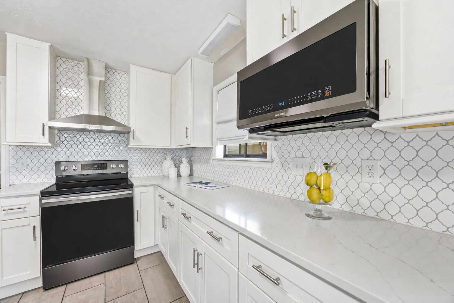 Quartz counters and a patterned backsplash bring subtle texture to the kitchen’s clean, modern palette