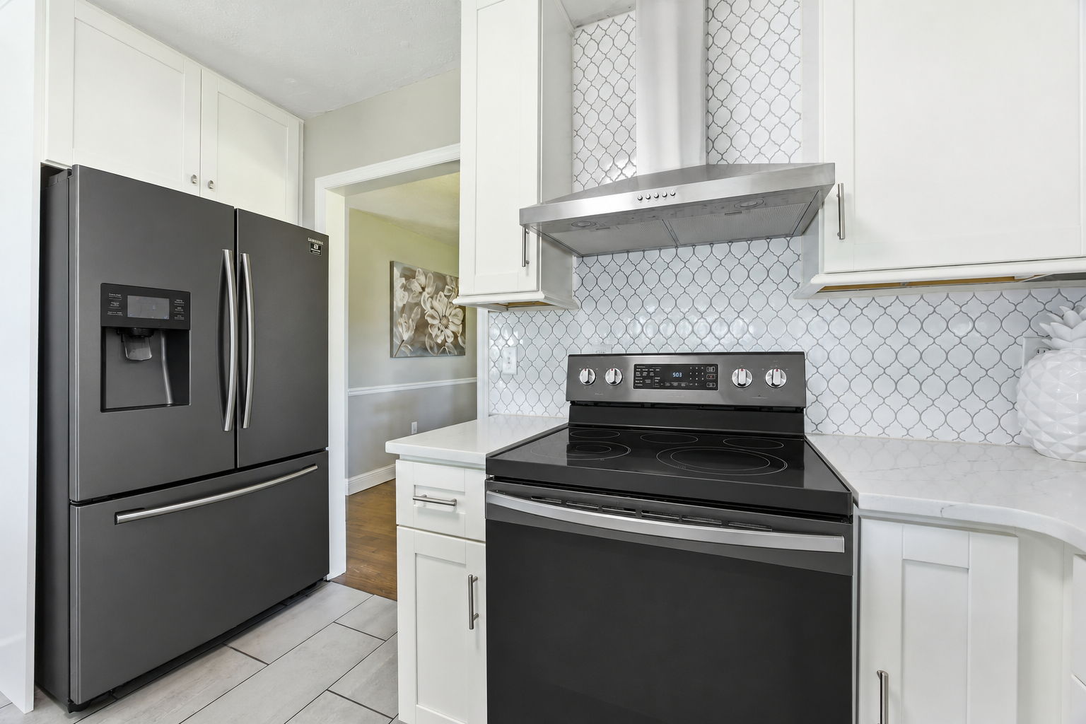 Dark appliances and a stainless hood add polished contrast among the bright cabinetry and finishes