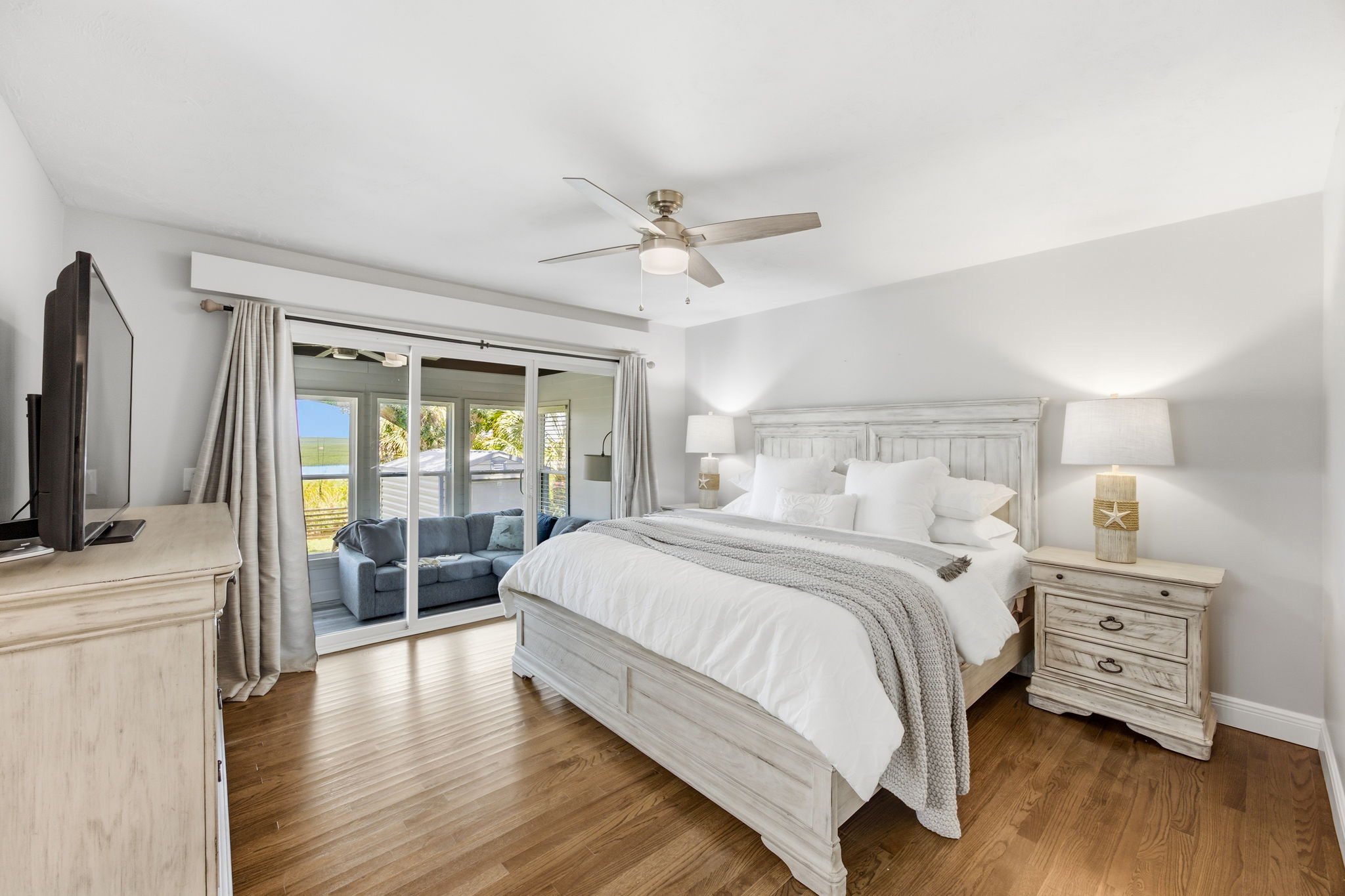 The primary bedroom feels calm and private, with oak floors and direct access to the enclosed sun porch