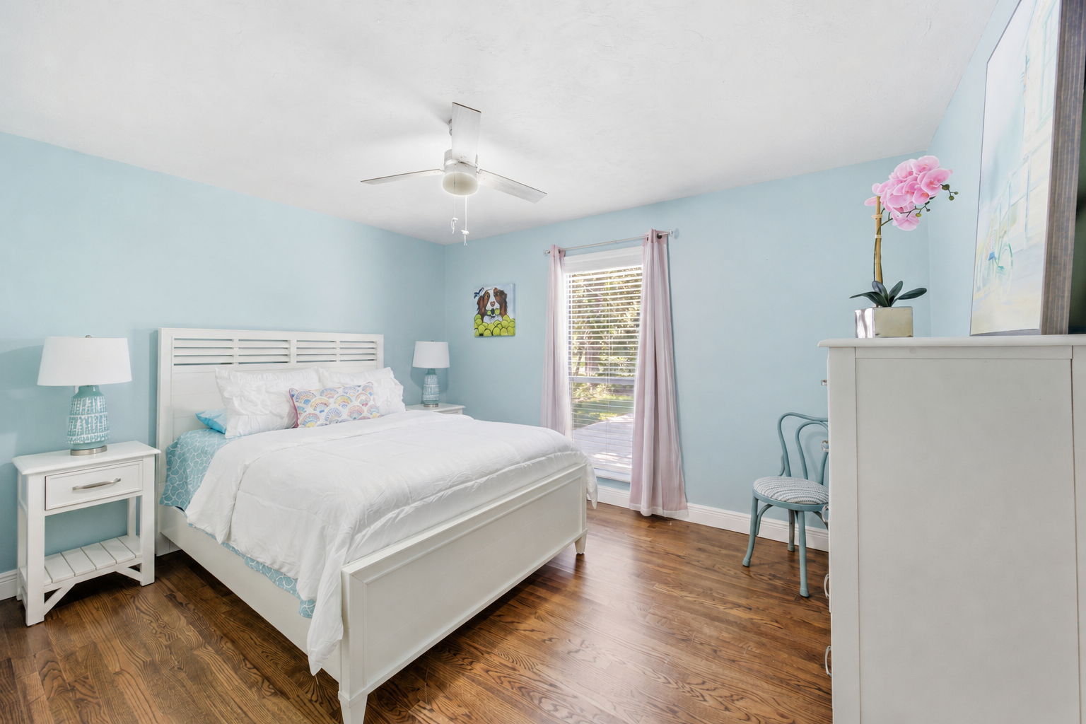 The second guest bedroom brings a brighter coastal character while preserving the warmth of the oak floors