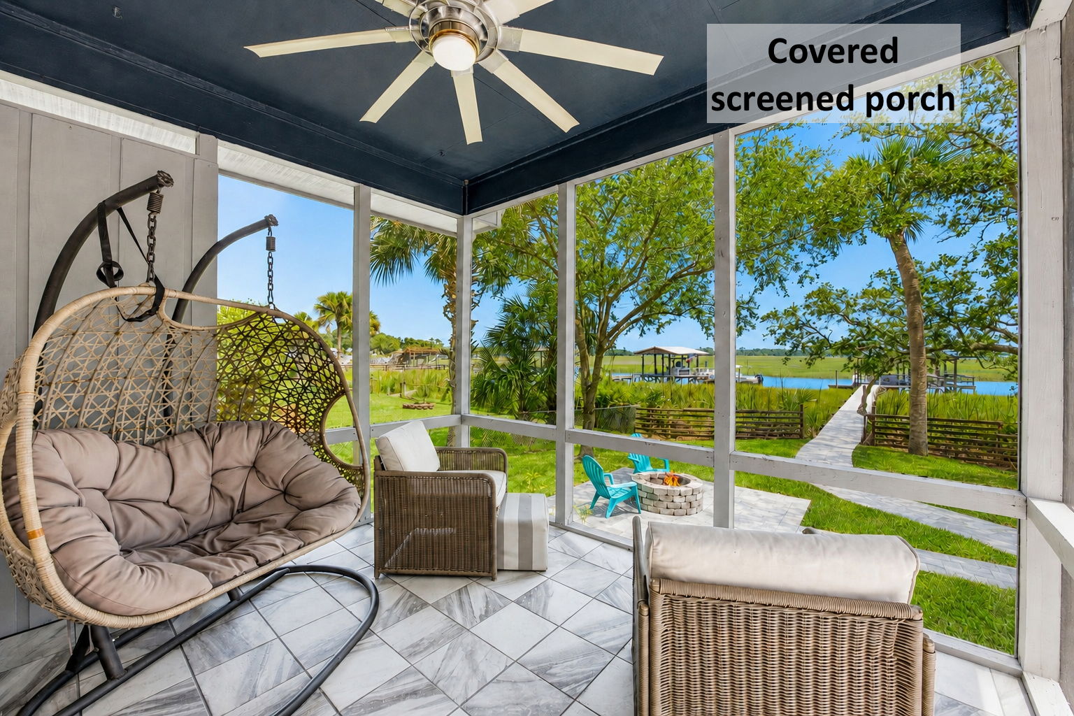 Outdoor living begins on the covered screened porch, where the marsh and private dock stay beautifully in view