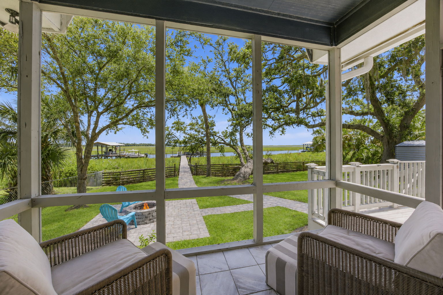 By day, the porch frames a clear sightline across the lawn, firepit and private walkway to the dock