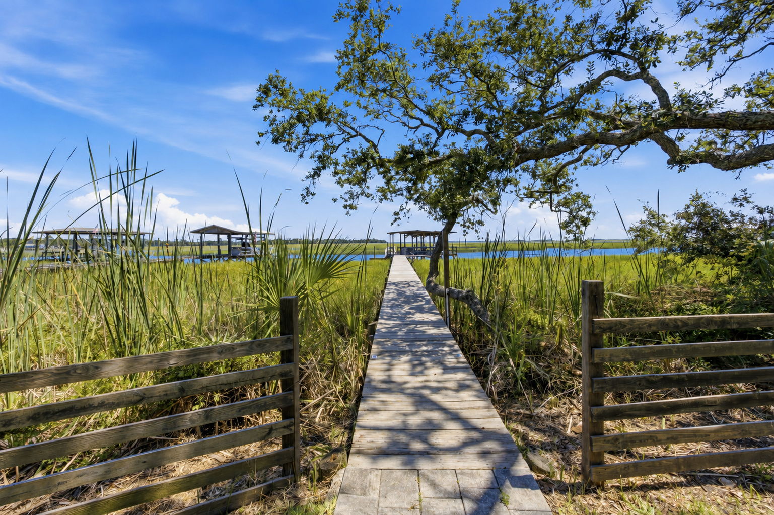 A private walkway leads through the marsh, drawing you from the backyard directly toward the dock