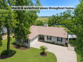 … where a welcoming single-story home rests beneath mature oaks, with marsh and river views just beyond