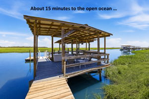 Out back, a private covered dock and boat lift make days on the water effortless, with the ocean about 15 minutes away