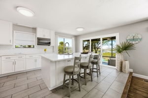 The renovated kitchen begins with a generous island, crisp finishes and waterfront views beyond the screened porch