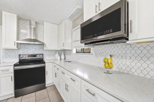 Quartz counters and a patterned backsplash bring subtle texture to the kitchen’s clean, modern palette