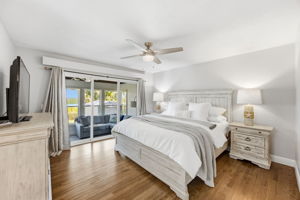 The primary bedroom feels calm and private, with oak floors and direct access to the enclosed sun porch