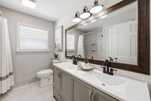 The renovated guest bath pairs a double vanity with shiplap detail, crisp finishes and thoughtful storage