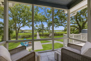By day, the porch frames a clear sightline across the lawn, firepit and private walkway to the dock