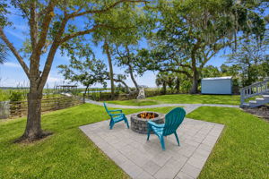 Just beyond, a shaded firepit terrace creates an inviting place to gather beneath the mature oaks