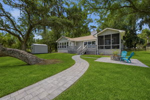 A curving paver path ties together the deck, porch and firepit while guiding the eye toward the water