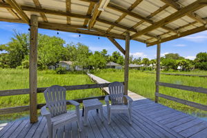 Looking back, the covered dock offers a shaded place to relax with the home tucked quietly beyond the marsh