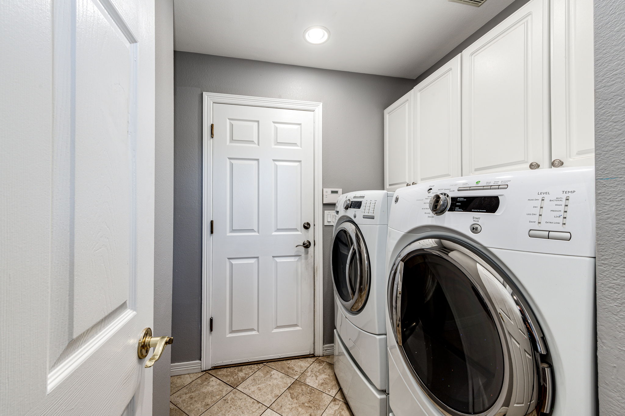 Separate area for laundry with cabinets. View of the door leading into the garage. All appliances stay!