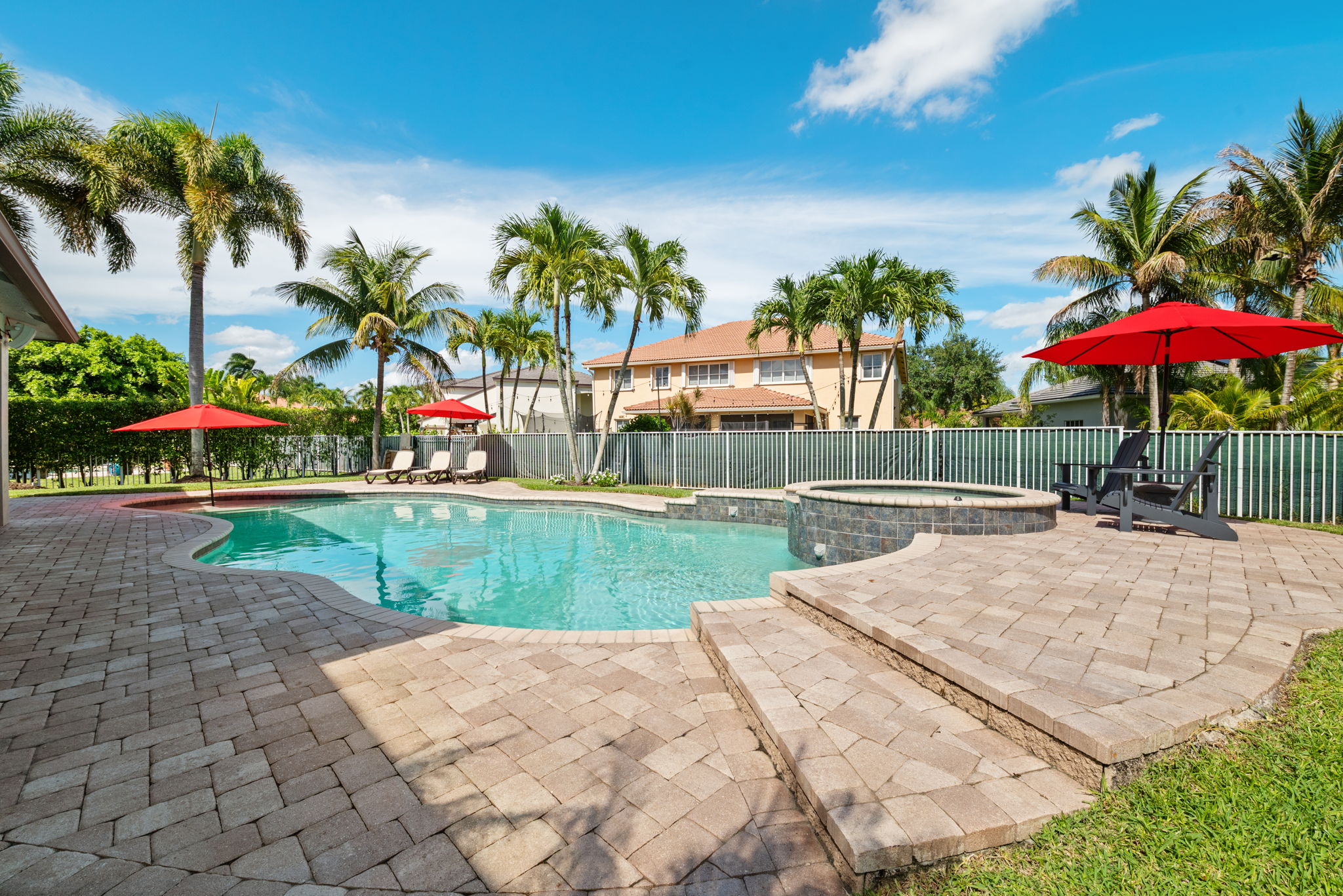 Freeform heated pool and overflow spa surrounded by paver patio.