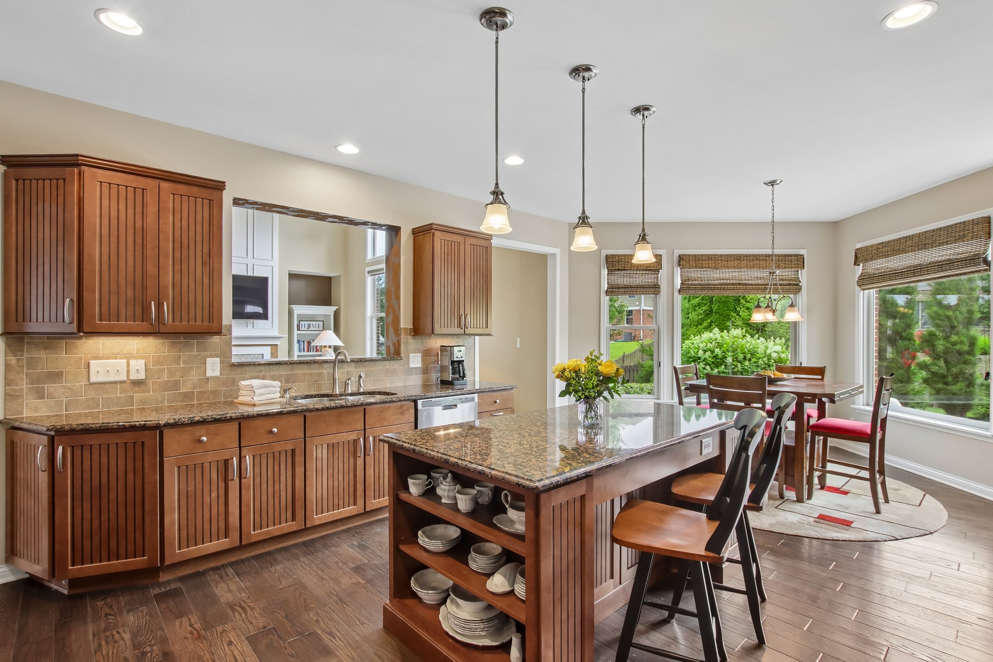 Center island offers open shelving and bar seating with pendant lighting