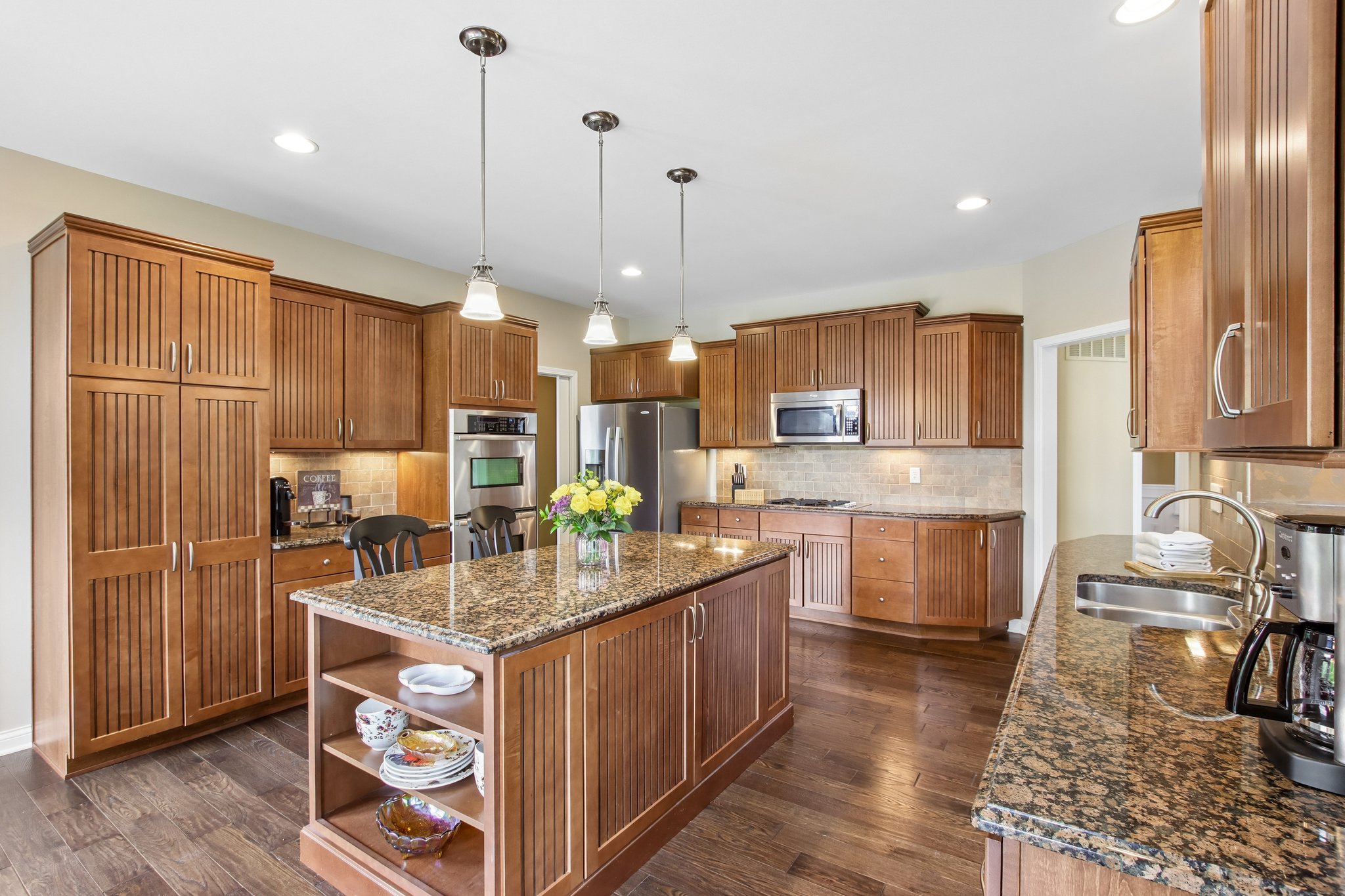 Kitchen offers hardwood flooring and functional layout with island, coffee bar area and tons of natural light