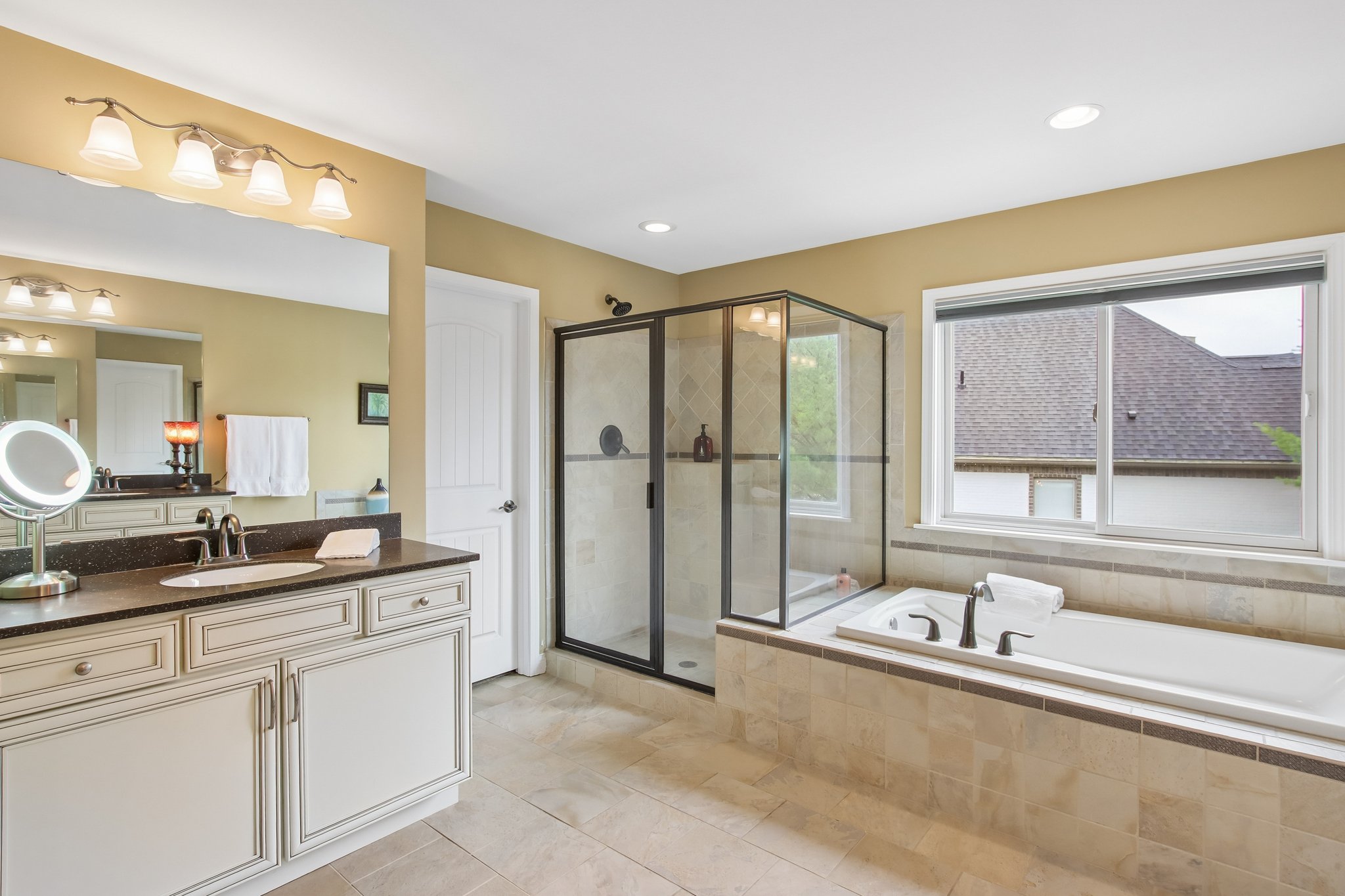 Primary Bathroom offering separate vanities, large custom tiled shower, deep soaking tub, and a large walk-in closet