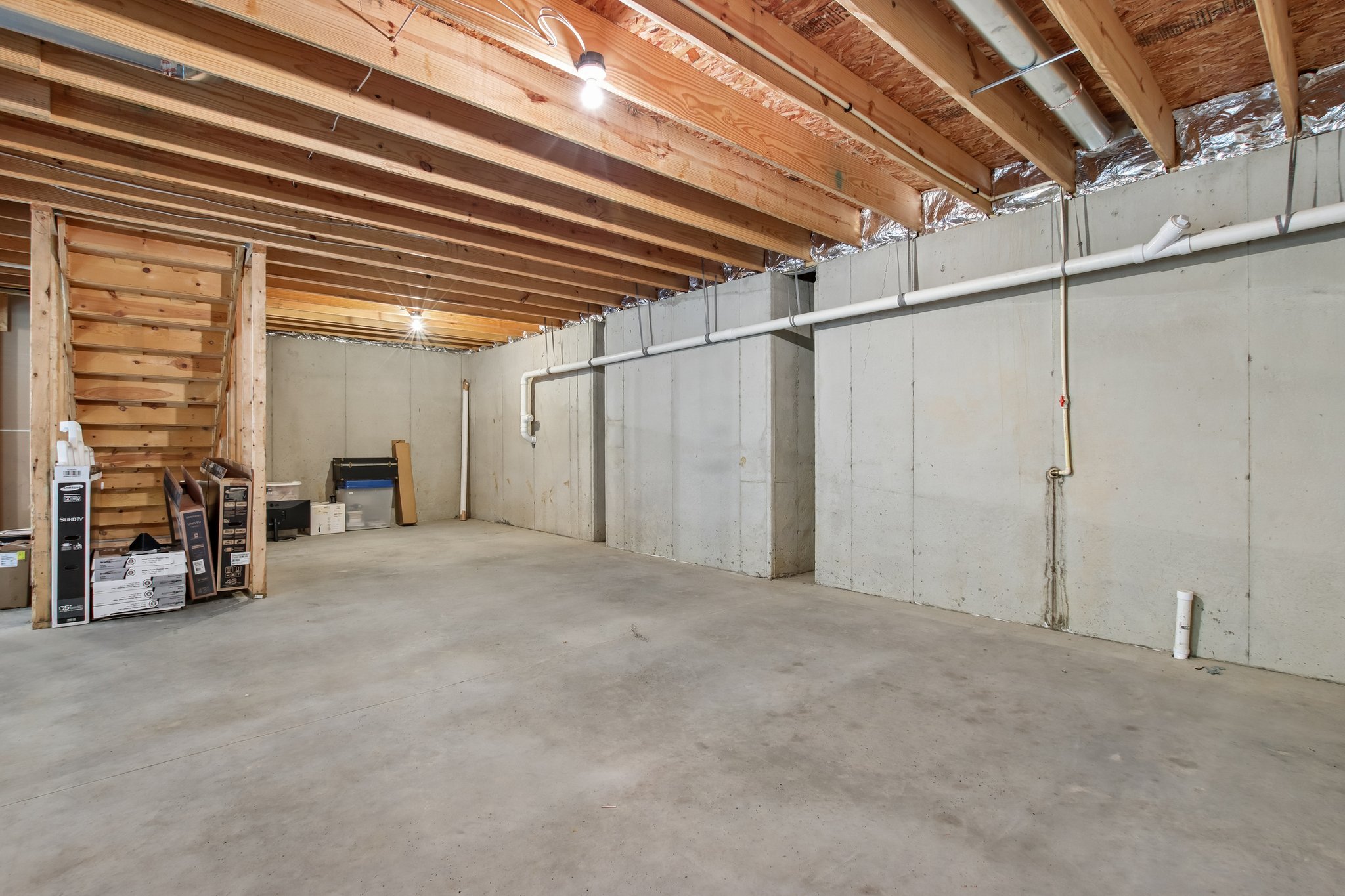 View of the unfinished lower level - 2 egress windows, plumbed for full bathroom, and wet bar